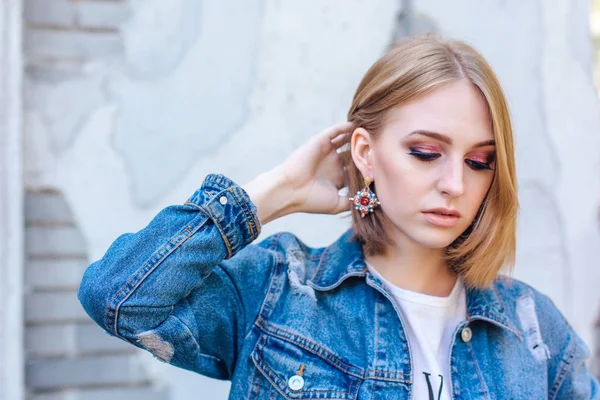 Büyük boy kot ceket ve güzel kulak yüzük tuğla duvara yakın duran kız moda.