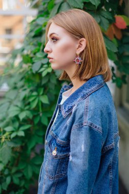 Moda kız açık havada büyük boy kot ceket ve güzel kulak yüzük ayakta.