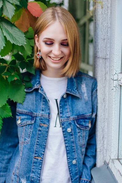 Moda kız açık havada büyük boy kot ceket ve güzel kulak yüzük ayakta.