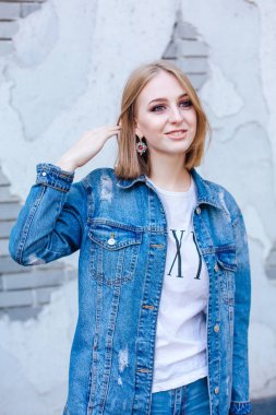 Büyük boy kot ceket ve güzel kulak yüzük tuğla duvara yakın duran kız moda.