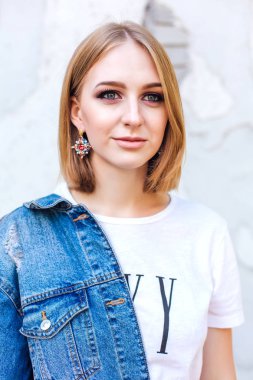 Büyük boy kot ceket ve güzel kulak yüzük tuğla duvara yakın duran kız moda.