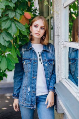 Moda kız açık havada büyük boy kot ceket ve güzel kulak yüzük ayakta.