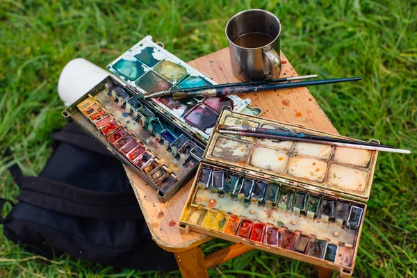 Palette of watercolor paints and brushes on the wooden background. — Stock Photo, Image