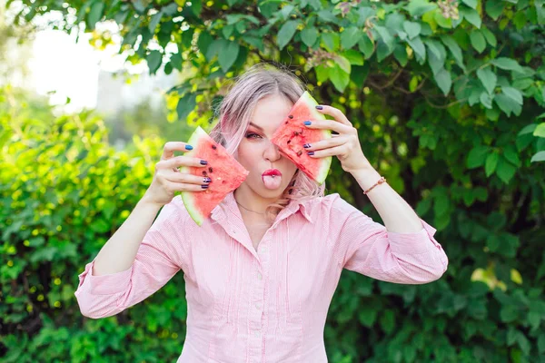 Hermosa joven con el pelo rosa sosteniendo dos rebanadas de sandía en frente de su cara — Foto de Stock