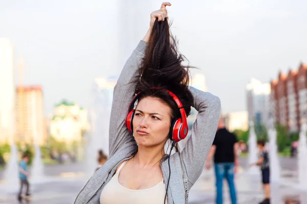 Girl listening to music streaming with headphones and making funny face.