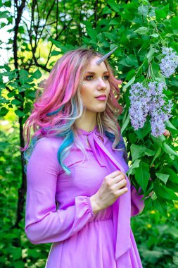 Gökkuşağı saç ve parlak makyaj Lila çiçek tutan olan peri kız at.