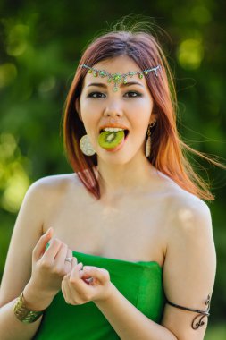 Güzel genç Asyalı kadın ile dilim kivi ağzına