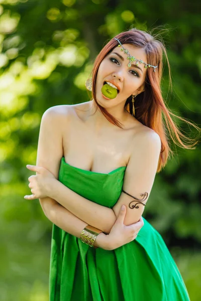 Vacker ung asiatisk kvinna med skiva kiwi i munnen — Stockfoto