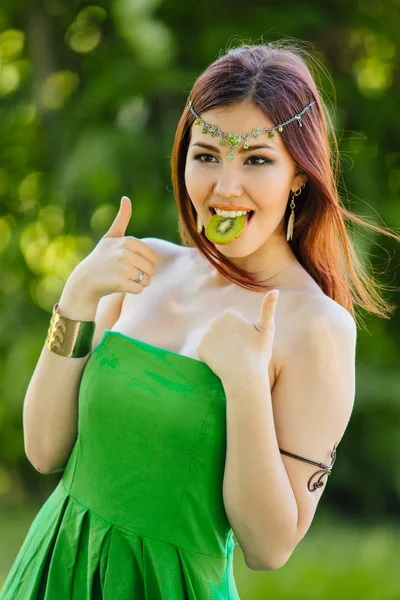 Vacker ung asiatisk kvinna med skiva kiwi i munnen — Stockfoto