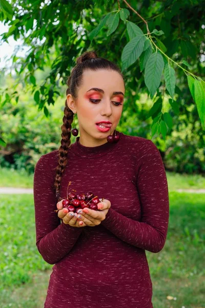 Mooie jonge vrouw met lange vlecht en natuurlijke cherry oorbellen. — Stockfoto