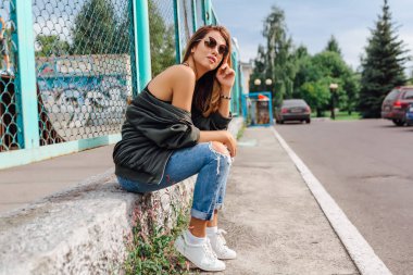 Güneş gözlüğü, salonları ve şehrin bombardıman ceket kot giyen trendy genç kadın moda portre