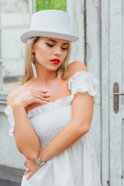 Sexy novia moderna en sombrero de cilindro blanco de pie junto a la vieja puerta vintage y ventana de espejo . — Foto de Stock
