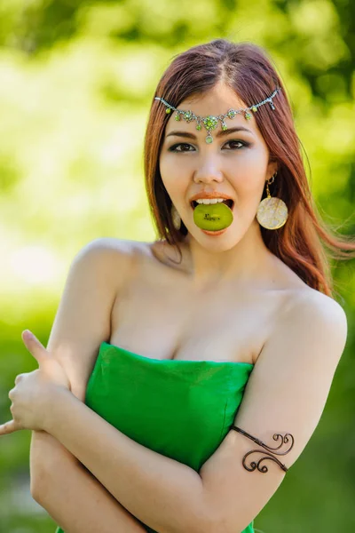 Hermosa joven asiática mujer con rebanada de kiwi en la boca — Foto de Stock