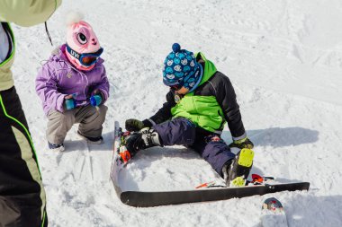 Sheregesh, dağ Shoria, Kemerovo bölgesi, Rusya Federasyonu - 6 Nisan 2018: yamacında küçük kız kardeşi ile oturan küçük çocuk dağ Kayak rider