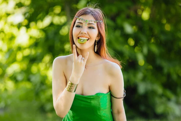 Yeşil Elbise Diadema Dilim Kivi Ağzına Tutarak Kafasına Güzel Genç — Stok fotoğraf