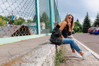 Güneş gözlüğü, salonları ve şehrin bombardıman ceket kot giyen trendy genç kadın moda portre