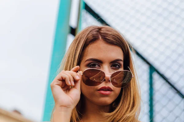 Mode Porträtt av trendiga ung kvinna som bär solglasögon, jeans med hallar och bombplan jacka i staden — Stockfoto