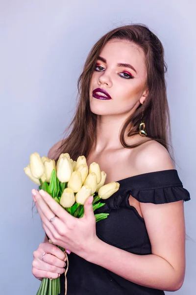 Ritratto di bellezza di una donna con brillante trucco colorato e bouquet di tulipani gialli — Foto Stock