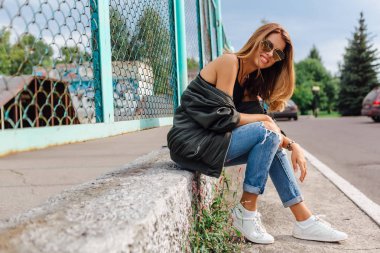 Güneş gözlüğü, salonları ve şehrin bombardıman ceket kot giyen trendy genç kadın moda portre