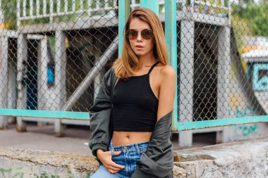 Güneş gözlüğü, salonları ve şehrin bombardıman ceket kot giyen trendy genç kadın moda portre