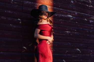 Bir tren ve ışık ışını siyah şapka ayakta uzun kırmızı bir gece elbisesi güzel genç kadın