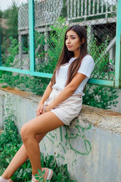 Портрет девушки, сидящей рядом с забором Рабица — стоковое фото