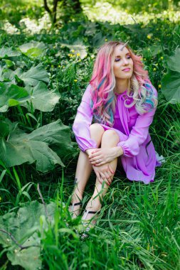 Gökkuşağı saç ve parlak makyaj çimlere oturup olan peri kız at.