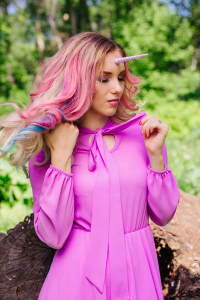 Fairy girl unicorn with pink hair in summer forest