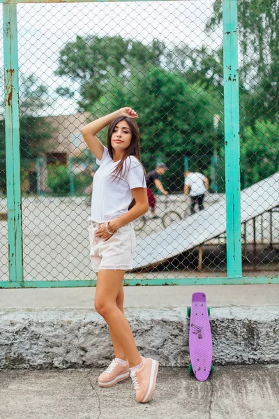 彼女のプラスチック製の scateboard と scateboard 申し立てしている隣に立っているトレンディなプリティ少女の夏のライフ スタイル イメージ. — ストック写真