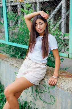 Sıva çitin yanında oturan bir yağma kız portresi