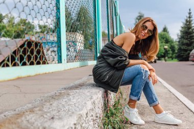 Güneş gözlüğü, salonları ve şehrin bombardıman ceket kot giyen trendy genç kadın moda portre