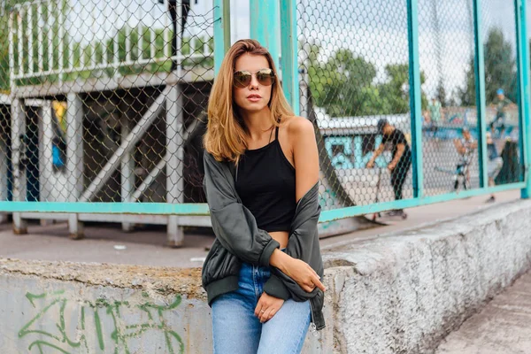 Güneş gözlüğü, salonları ve şehrin bombardıman ceket kot giyen trendy genç kadın moda portre — Stok fotoğraf