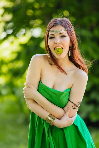 Vacker ung asiatisk kvinna med skiva kiwi i munnen — Stockfoto