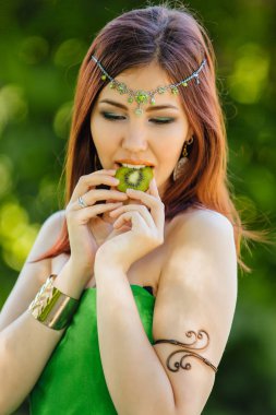 Güzel genç Asyalı kadın dilim kivi ısırma