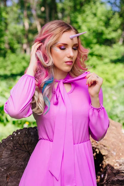 Fairy girl unicorn with pink hair in summer forest