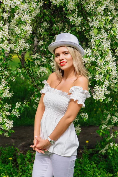 Sexy novia moderna en sombrero de cilindro blanco que ordena flores de manzano bloomin . — Foto de Stock