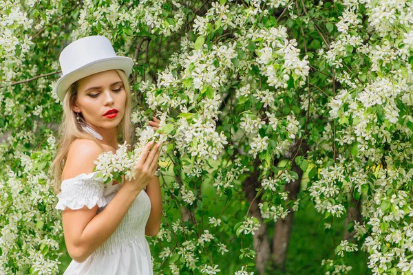 性感现代新娘在白色圆筒帽子 enjoing 了不起苹果树花. — 图库照片