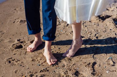 Kumlu sahilde duran düğün çiftin ayak.