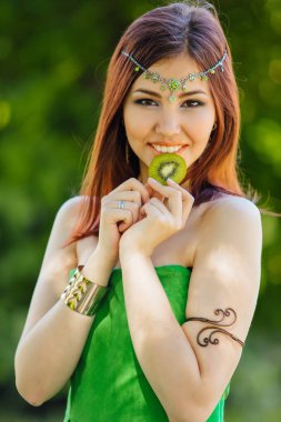 Güzel genç Asyalı kadın dilim kivi ısırma