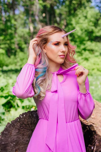 Fairy girl unicorn with pink hair in summer forest