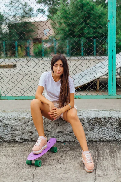 Obraz životního stylu letní módní hezká mladá dívka sedící vedle coart skateboard s její plastový skateboard. — Stock fotografie