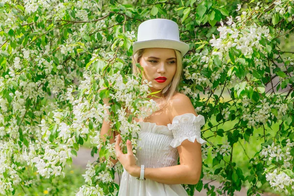 Sexy novia moderna en sombrero de cilindro blanco que ordena flores de manzano bloomin . —  Fotos de Stock