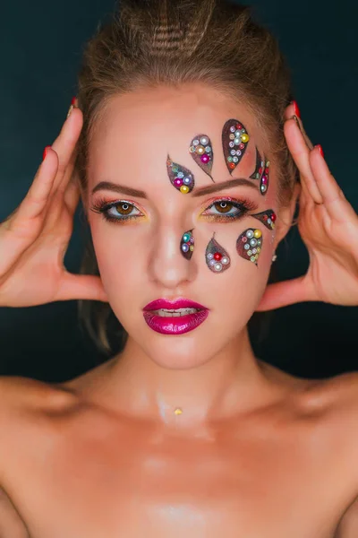 Hermosa mujer joven con flor cara de arte. Maquillaje de primavera. Maquillaje de vacaciones de mujer creativa con destellos y cristales decorativos — Foto de Stock