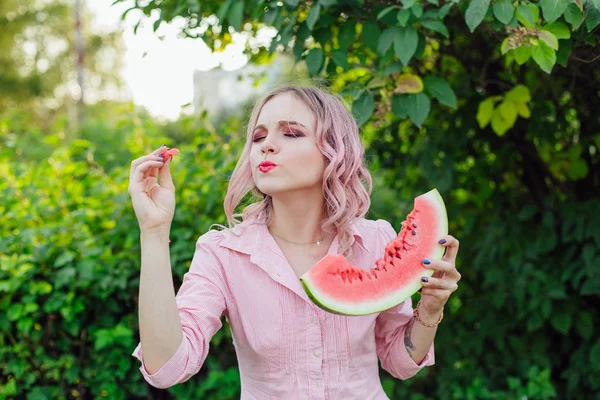 Beautiful young woman with pink hair enjoying watermelon — Stock Photo, Image