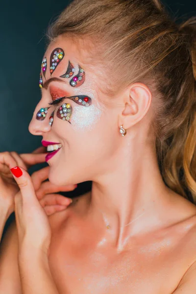 Vacker ung kvinna med blomma ansikte konst. Våren makeup. Kreativ kvinna holiday make-up med sparles och dekorativa kristaller — Stockfoto