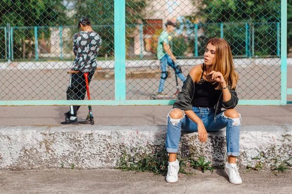 Модный портрет модной молодой женщины в солнцезащитных очках и пиджак подрывника, сидящего рядом с Рабицем в городе — стоковое фото