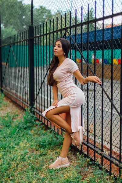 Ritratto di una ragazza di lusso in piedi accanto alla recinzione di ferro — Foto Stock