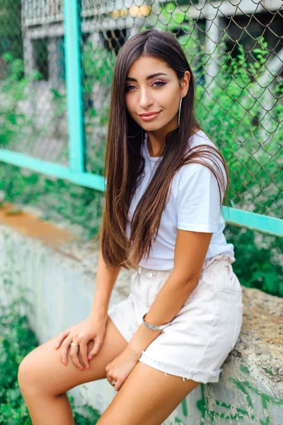 Портрет девушки, сидящей рядом с забором Рабица — стоковое фото