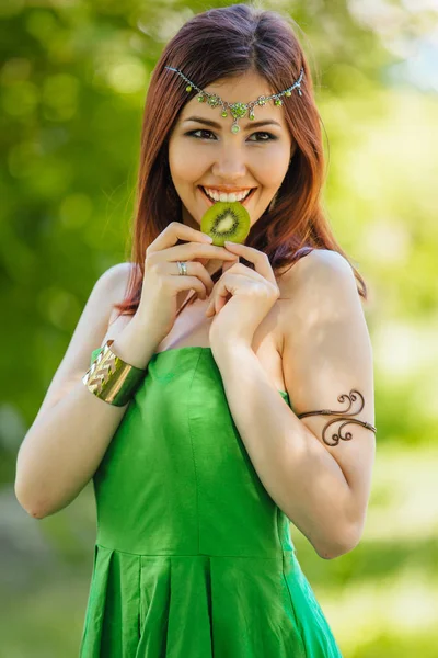Vacker ung asiatisk kvinna bita skiva kiwi — Stockfoto