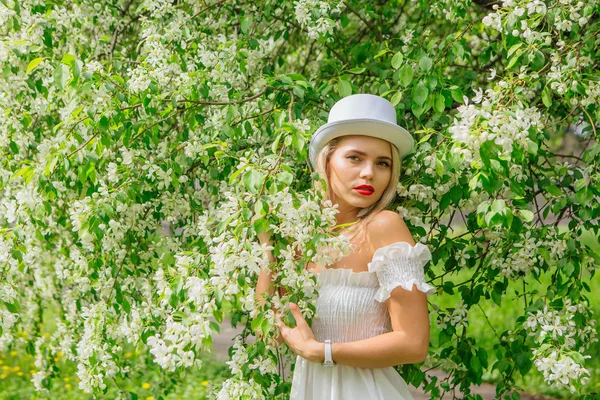 Sexy moderne bruid in witte cilinder hoed enjoing bloomin apple boom bloemen. — Stockfoto